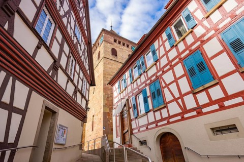 Historic half-timbered houses with blue shutters and tower view in a narrow lane, Ötisheim,