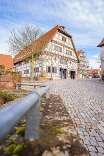 Traditional half-timbered house on cobblestone road under blue sky, Ötisheim, Enzkreis, Germany