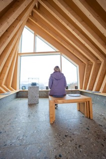 Person sitting on a bench in a modern wooden room with window view, Sinnraum, Oberreute, Allgäu,