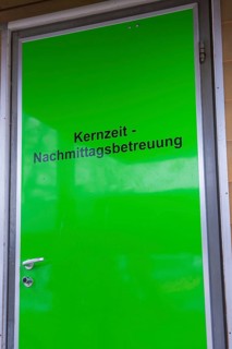 Green door with inscription for core time afternoon care, easy entrance, homework supervision,