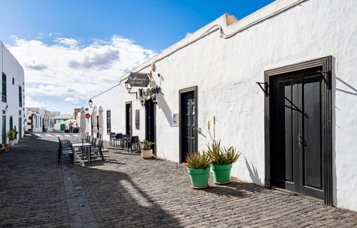 Typical white houses with colored doors and windows, alley with restaurant, Teguise, Lanzarote,