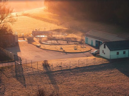 Sewage treatment plant in a meadow in soft sunlight, with fog and shade, quiet and idyllic,