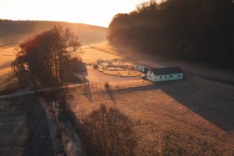Sewage treatment plant in a meadow surrounded by trees at sunset, rural and peaceful atmosphere,