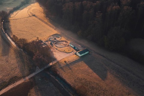 Wastewater treatment plant buildings and ornate paths in the middle of fields from a bird's eye