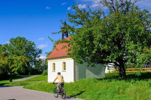 Cyclists in front of a chapel, Steingaden, near Sulzberg, Oberallgäu, Swabia, Bavaria, Germany