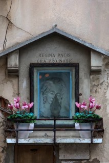 Half relief of the Madonna in a niche with floral decoration, text: Queen of Peace Pray for Us,