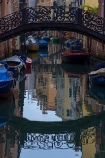 Wrought iron bridge reflected in the canal, Venice, Veneto, Italy