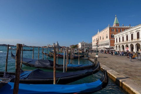 Gondolas in front of the Doge's Palace, Santa Maria della Salute in the back, blue sky, Venice,