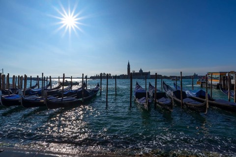 Gondolas at anchor, beginning floods, San Giorgio Maggiore church in the back, sun star, Venice,