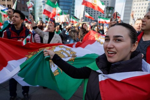 Iranians demonstrate with a large imperial Iranian flag on the day of the US and Israeli attack on
