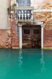 Dilapidated house façade with balcony and door on the canal during floods, Venice, Veneto, Italy