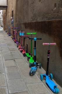 Parked colorful children's scooters, scooters on a wall in front of a kindergarten, Venice, Veneto,