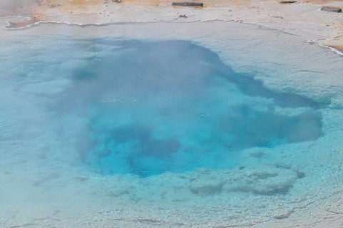 Blue hot spring surrounded by steam and natural geology, Yellowstone National Park, Wyoming, USA