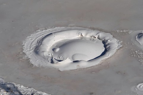 Close-up of gray mud pot with rising bubbles and geothermal features, Yellowstone National Park,