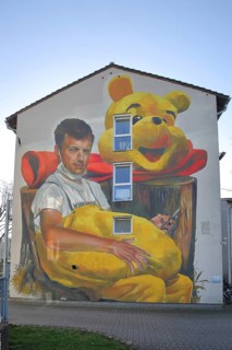 Mural Waldsterben by CASE MaClaim 2024, man with yellow plush toy, bear figure, street art,