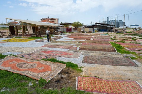Open-air market with a variety of carpets spread across grasses and pebbles, Aksaray province,