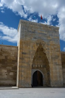Decorated medieval gate in a high stone wall under a clear sky, richly decorated portal of the