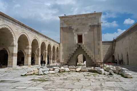 Open courtyard with arched architecture and scattered ancient stones, Sultanhani caravanserai, on