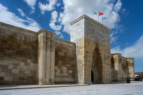 Historic stone architecture with massive gate and towers under a sunny sky, portal of the