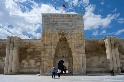 Detailed historic gate with stone walls and people in the foreground, richly decorated portal of