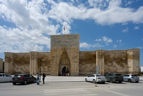 Historic fortress with an open gate, cars and passers-by in the foreground, Sultanhani