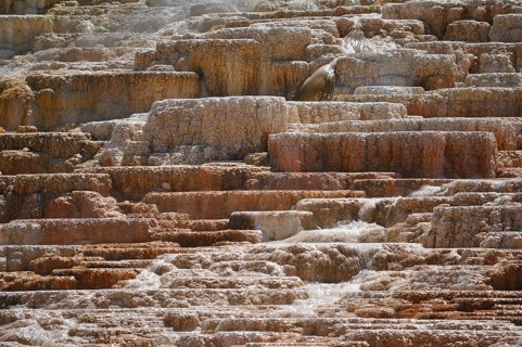 Stepped brown-yellow terraces of volcanic deposits with running water, Yellowstone National Park,