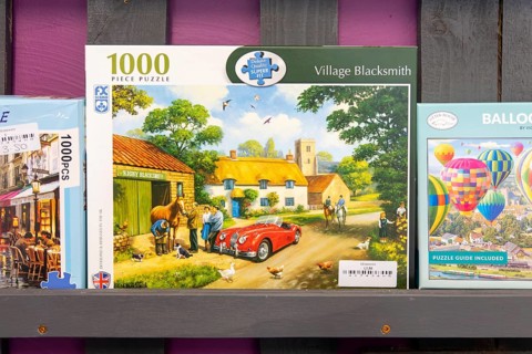 Boxed jigsaw puzzles on display in secondhand charity shop, UK