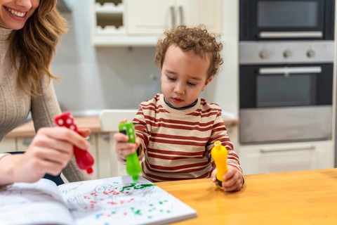 Mother and young child engaging in fun coloring activities at a kitchen island, using colorful dot