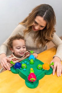 Happy mother and young son share joyful indoor play, laughing while learning with a colorful turtle