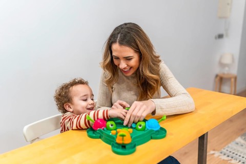 Mother and young son enjoying a playful moment, laughing and interacting while sitting at a wooden
