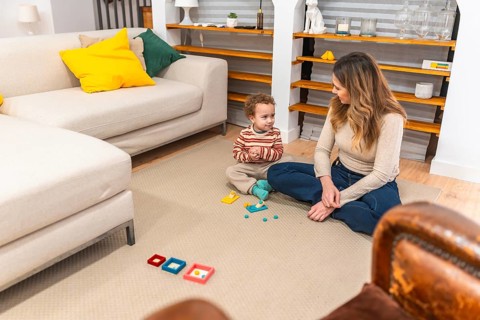 Mother and toddler sitting on the floor in their living room, engaging in educational play with