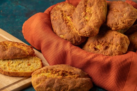 Fresh potato rolls in a basket with orange cloth, one cut open