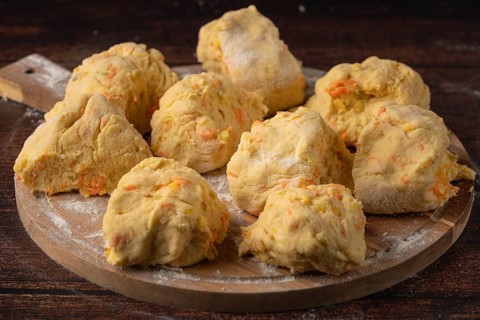Several pieces of dough on a floured wooden board to prepare for baking