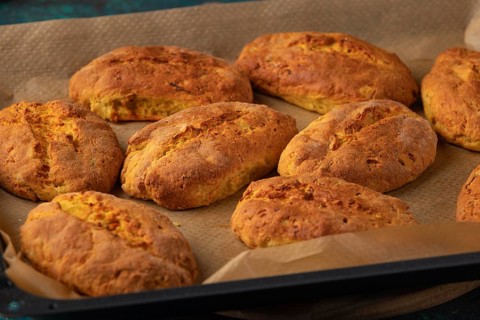 Freshly baked potato rolls on a baking tray lined with baking paper