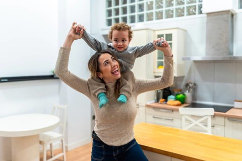 Mother enjoying playtime with her son on a piggyback ride at home, sharing laughter and bonding