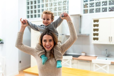 Happy mother giving her young son a piggyback ride, both smiling and interacting with joy and love