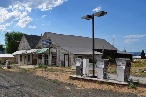 Abandoned gas station with old gas pumps in front of a rural shop, Unity, Oregon, USA