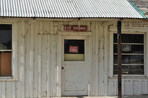 Old white door with 'Rest Rooms and Sorry We're Closed' signs on a wooden building, Stratton's