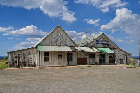 Two connected weathered buildings, Stratton's Store store, under blue sky with scattered clouds,