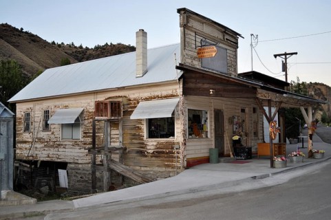 An old, weathered timber house on a hillside with a covered porch and chimney, Mitchell, Oregon,