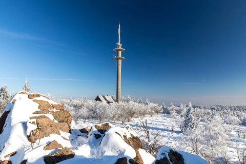 View from Großer Lugstein of the radio tower and the sunny winter landscape with snow-covered
