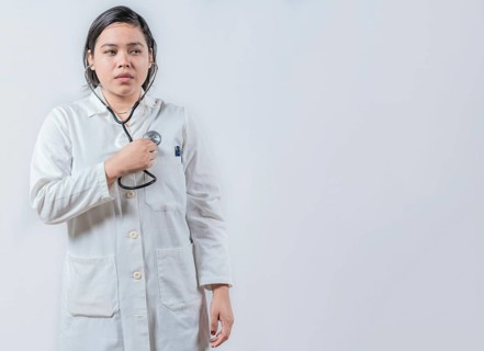 Asian Female Doctor Listening to Her Own Heartbeat with Stethoscope isolated. Young female doctor