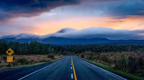 Mount Ngauruhoe in the morning at sunrise with glowing clouds, road SH 47, road sign, warning sign