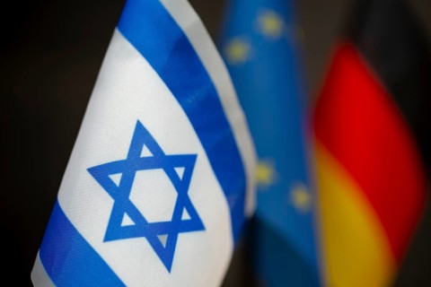 Close-up of the flag of Israel, blurred behind the flags of the EU and Germany