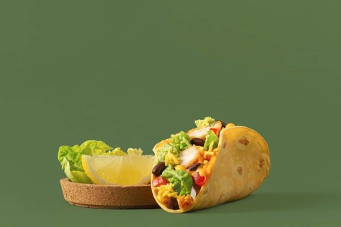 A vibrant taco filled with fresh vegetables, chicken, and cheese, complemented by slices of lemon