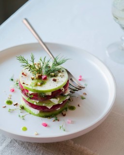 Top view of a delicately assembled gourmet salad, featuring layers of cucumber, radish, and feta