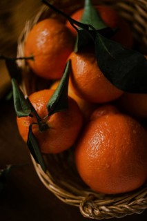 A close-up image capturing juicy oranges with vivid green leaves, nestled within a rustic woven