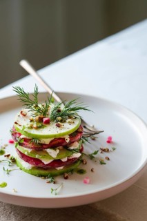 From above view of a gourmet salad featuring layers of green cucumber, red beetroot, and white
