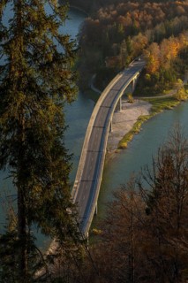 A picturesque Faller-Klamm Bridge gracefully arches over a serene river surrounded by vibrant