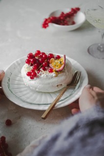 Cropped unrecognizable person's hands while serving a delicious red currant and passionfruit